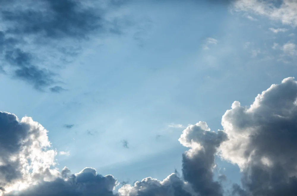 Licht zwischen Wolken und blauem Himmel als Sinnbild für Ruhe, Weite und Auftanken in der Meditation